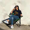 femme sur une chaise portant des lunettes de soleil et un tshirt upcyclé bleu avec des dessins jaunes